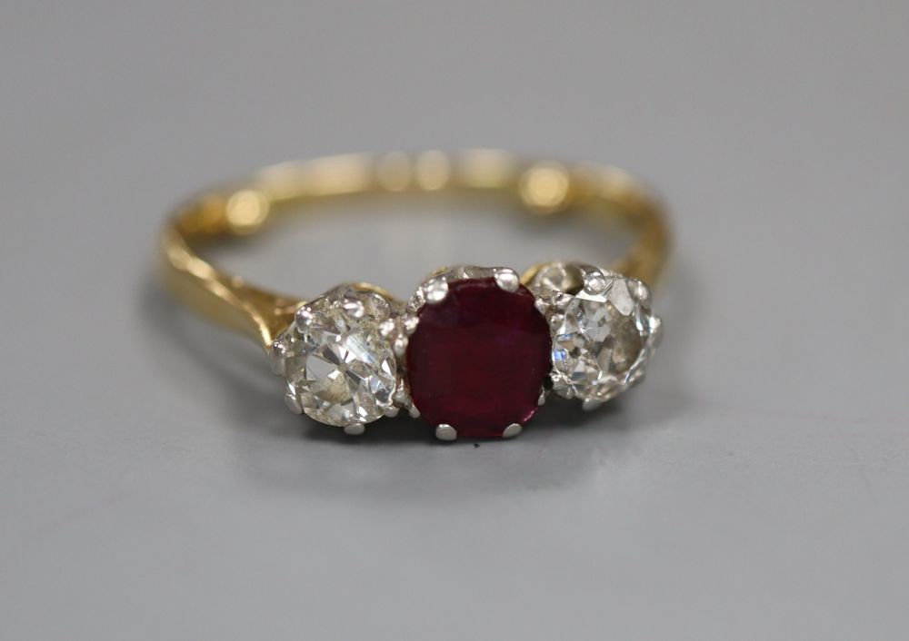 An 18ct and plat, ruby and diamond set three stone ring, size M/N, gross 3 grams.